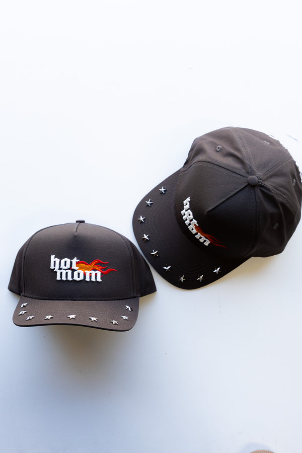 Two black baseball caps with text "hot mom" and flames with silver studs around brim