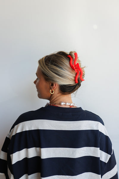 Person wearing a navy and white striped sweater with a red hair accessory against a plain background