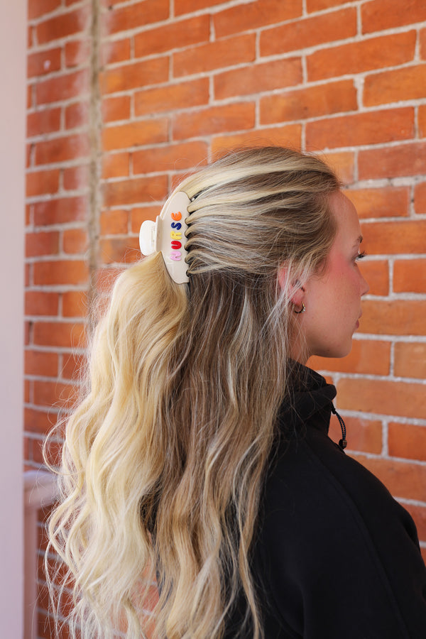 Woman with blonde hair styled in a claw clip with "NURSE" written on it.