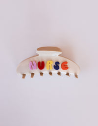 Hair clip with colorful letters spelling 'NURSE' on a white background