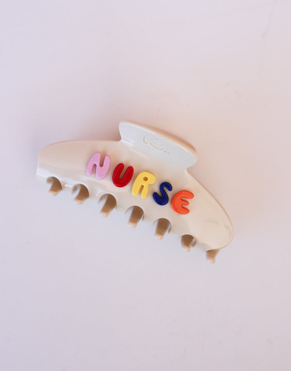 Cream hair clip with colorful letters spelling 'NURSE' on a white background