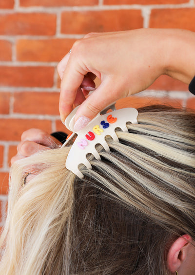 Person putting a "NURSE" claw clip in their hair.