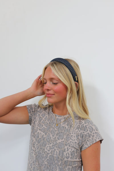 Woman wearing a denim headband with gold studs on it.