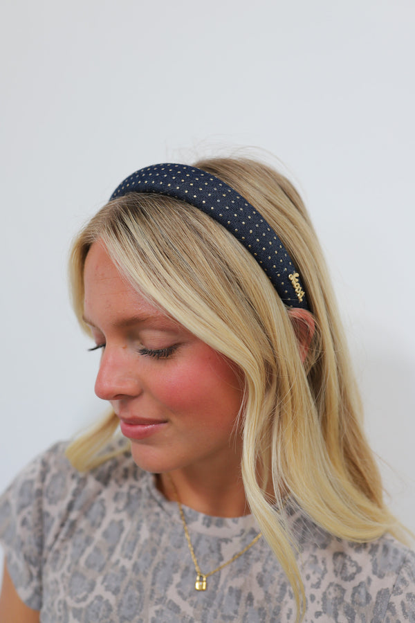 Girl wearing a denim padded headband with gold studs on it.