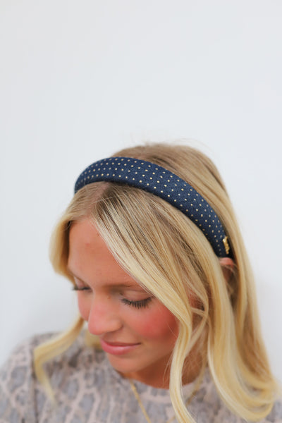 Woman wearing a denim headband with gold studs on a light background