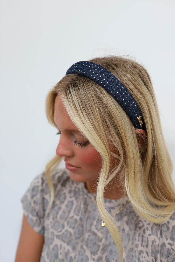 Woman wearing a denim headband with gold studs  against a white background