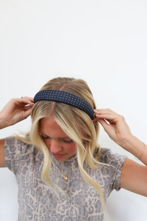 Woman wearing a denim headband with gold studs against a white background
