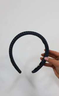 Denim headband with gold studs held against a white background.