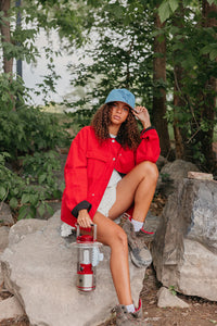 girl sitting on a rock wearing denim baseball cap with an eagle embroidered on it 