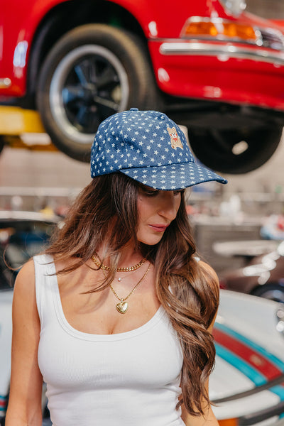 Woman wearing a blue star baseball cap with a red car in the background