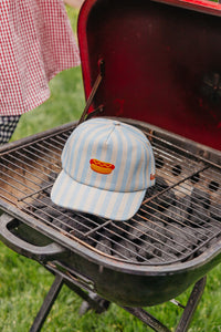 Striped baseball cap with a hot dog design on a grill