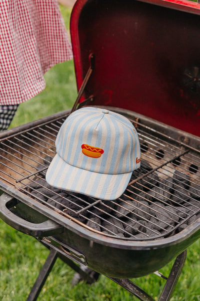 Striped baseball cap with a hot dog design on a grill
