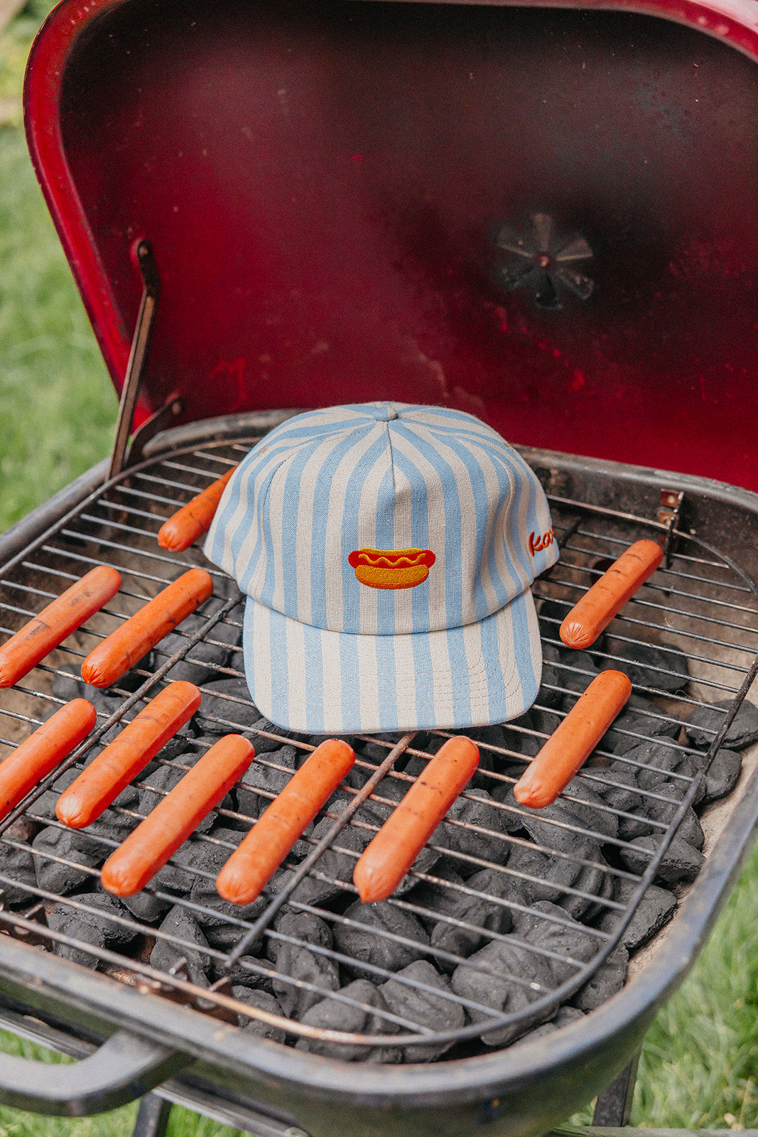 Cap with hot dog graphic on a grill with hot dogs