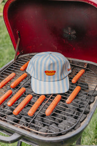 Cap with hot dog graphic on a grill with hot dogs
