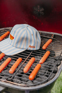 Striped cap on a grill with hot dogs