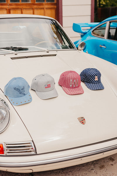 Four baseball caps on a vintage car with a blue car in the background