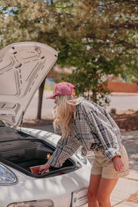 Person opening a car trunk with a red hat and plaid shirt