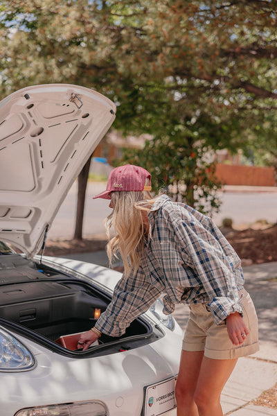 Person opening a car trunk with a red hat and plaid shirt