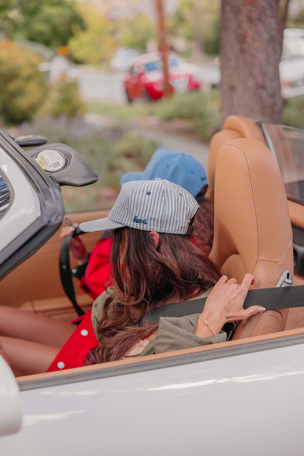 Two people in a convertible car with a blurred outdoor background