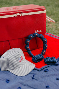striped baseball cap with an American flag embroidered on it next to a navy blue studded "get ready with me" headband and matching wristies