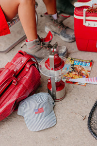 Red bag, cap with American flag, and other items on a concrete surface