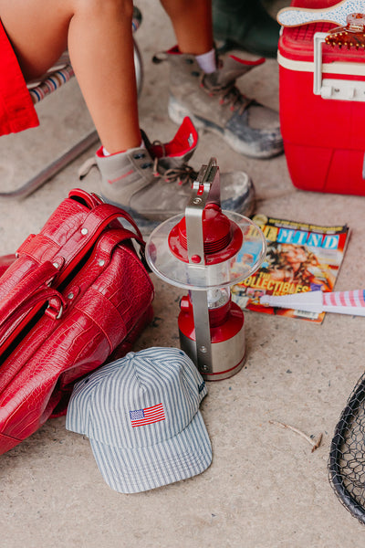 Red bag, cap with American flag, and other items on a concrete surface