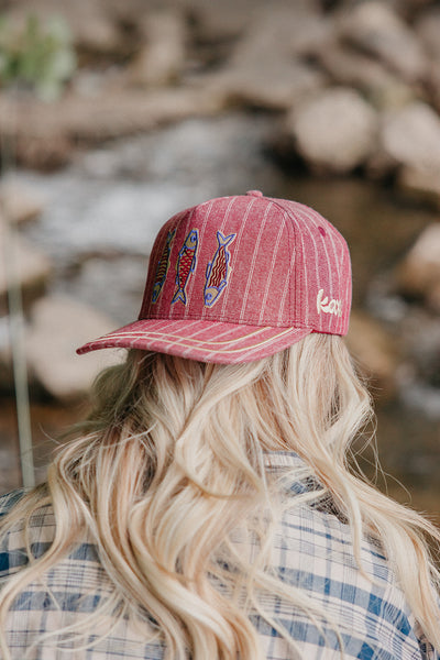 Person wearing a red cap with fish designs outdoors