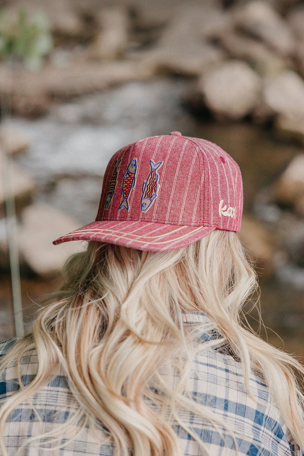 Person wearing a red cap with fish designs outdoors