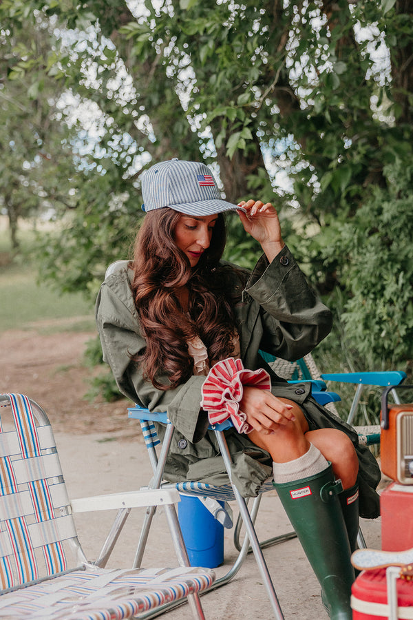 Woman sitting outdoors wearing a American flag baseball cap