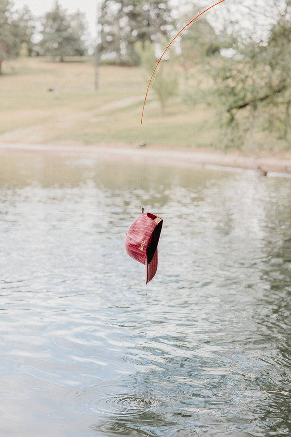 red baseball cap on a fishing line being pulled out of a lake