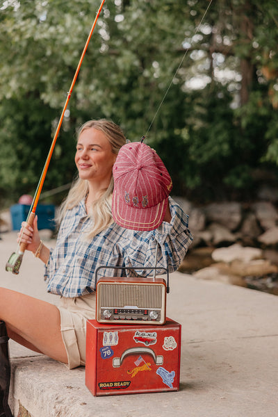 Woman holding a fishing rod with a red trucker hat on the fishing line