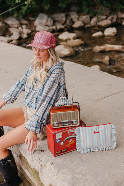 Woman sitting by a stream with a vintage radio and striped bag