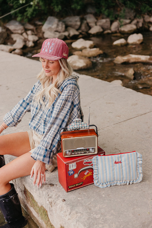 Woman sitting by a stream with a vintage radio and striped bag
