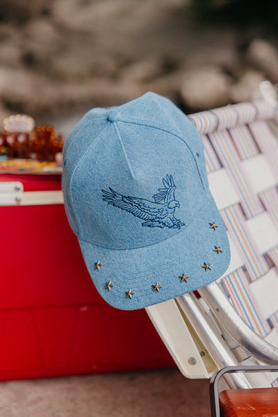 denim trucker hat with an eagle embroidered on it, with studs on the brim