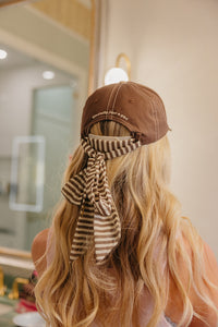 Person wearing a brown cap with a striped scarf in a bathroom setting