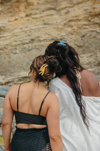 Two women with styled hair with hold everything claw against a rocky cliff.