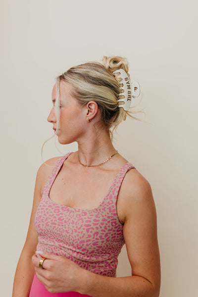 Woman wearing a pink leopard print top against a plain background wearing cream and brown Gym Girl claw