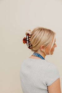 Woman with a bun wearing a brown HAIR GRL claw on a beige background