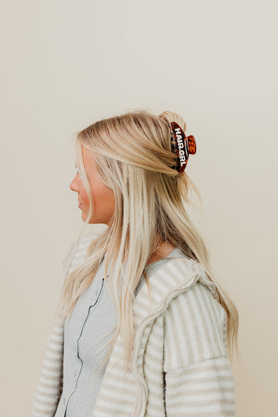Person with blonde hair wearing a brown Hair Girl claw clip against a plain background