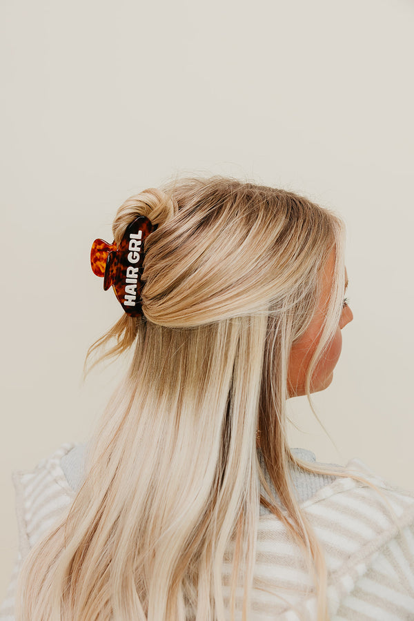 Person with blonde hair wearing a brown Hair Girl Claw Clip with text on a beige background