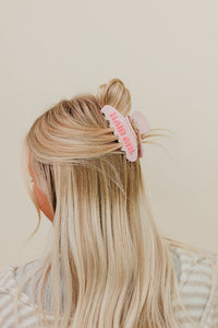 Blonde hair wearing a half up half down styled with a pink HAIR GRL claw clip