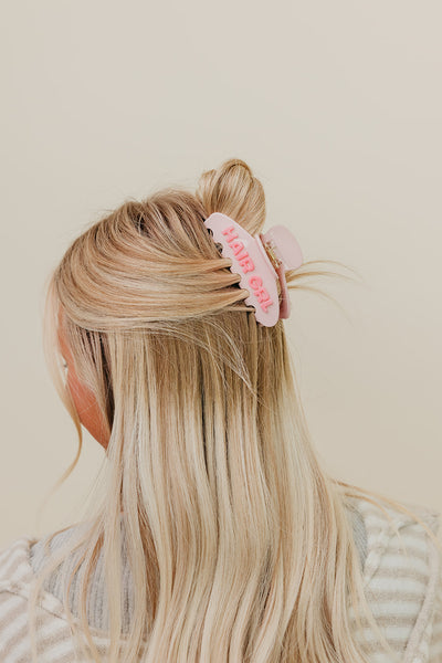 Blonde hair wearing a half up half down styled with a pink HAIR GRL claw clip